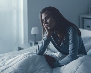 woman sitting up in bed looking dejected