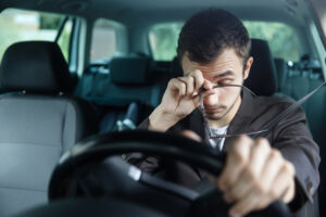 man rubbing eyes at the wheel