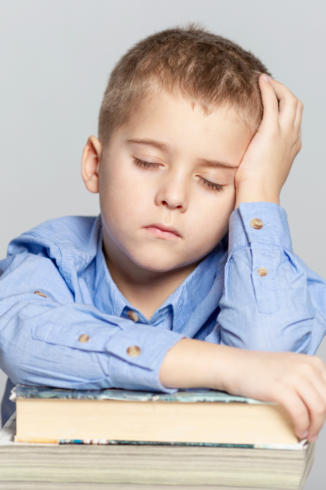 boy sleeping on stack of books