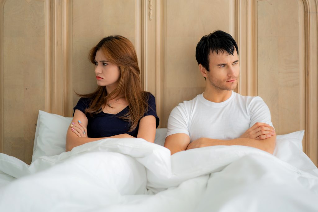 Couple in bed facing opposite directions after an argument