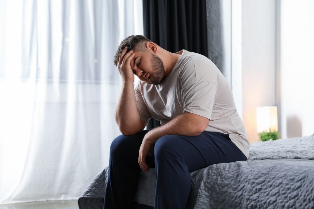 Tired overweight man on bed at home
