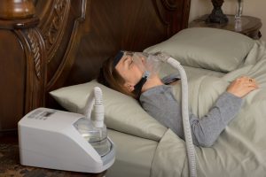 man sleeping in bed with full face CPAP mask