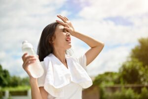 woman sweating outside holding water bottle