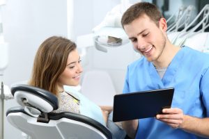 Girl in dentist's treatment chair while he goes over her patient forms